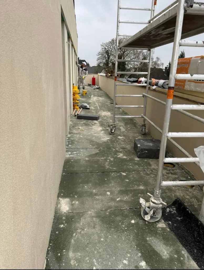 Aufgestelltes Gerüst an einer Außenwand, während der Außenputz arbeiten.