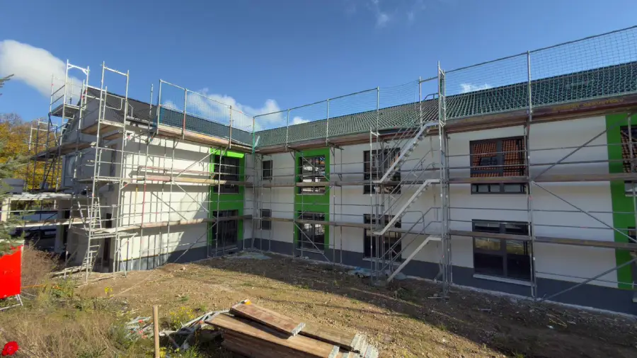 Aufgestelltes Gerüst an einer Außenwand, während der Außenputz arbeiten.