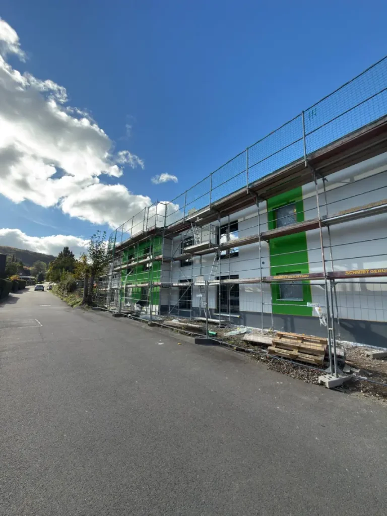 Straßenansicht mit aufgestelltem Gerüst, an einer Außenwand, während der Außenputz arbeiten.