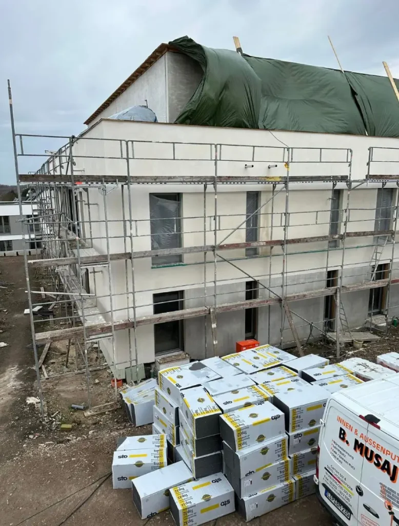 Amierung einer Außenwand, während der Arbeiten. Davor liegen Waren.