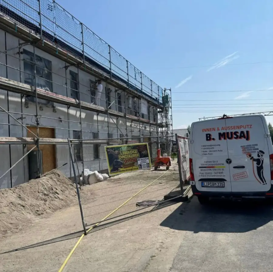 Straßenansicht mit aufgestelltem Gerüst an einer Außenwand, während der Außenputz arbeiten.