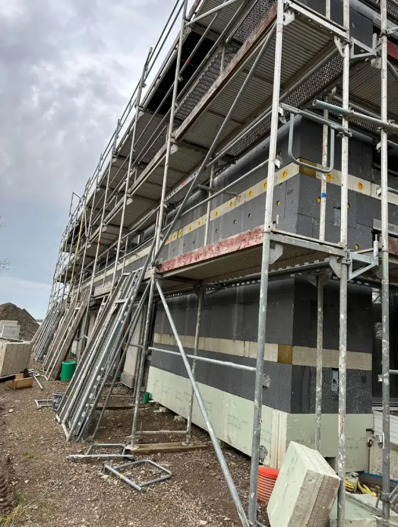 Nahaufnahme eines aufgestellten Gerüsts an einer Außenwand, während der Dämmarbeiten mit Wärmeverbundsystem.